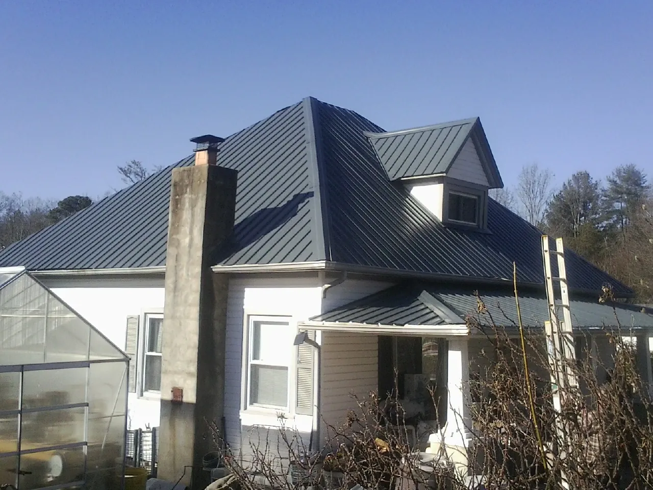 Dark blue standing seam metal roof on a white farmhouse with dormer — Slate & Tile Roof Repair by Roofing Brothers in Lisle