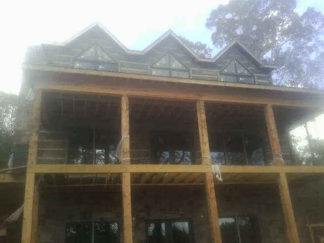 Dormers and porch framing on a large log home under construction — Roof Coating work by our crew in Lisle