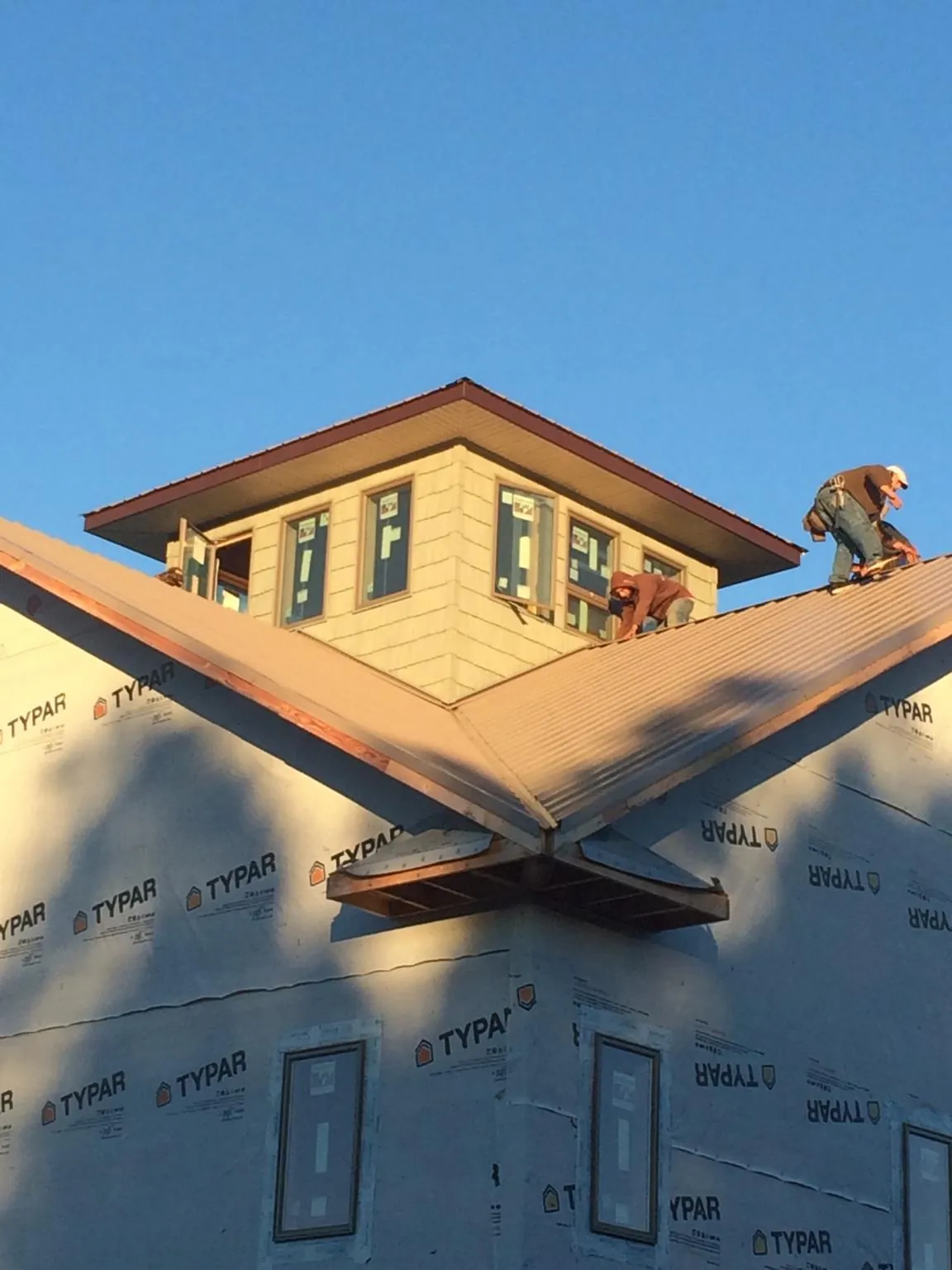 Roofers working around a rooftop cupola on a new metal roof at sunset — Roof Waterproofing in Lisle by Roofing Brothers